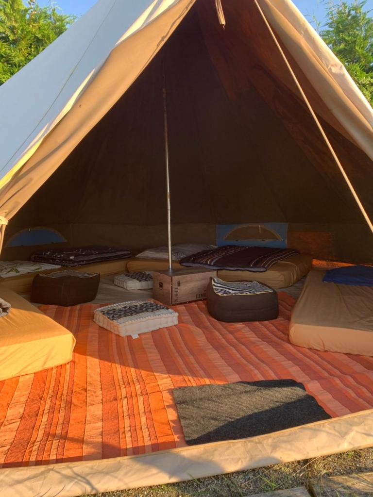 une tente avec un tas d'oreillers et de couvertures dans l'établissement La Tente Tipi au Ranch du Bonheur, à Tourtouse
