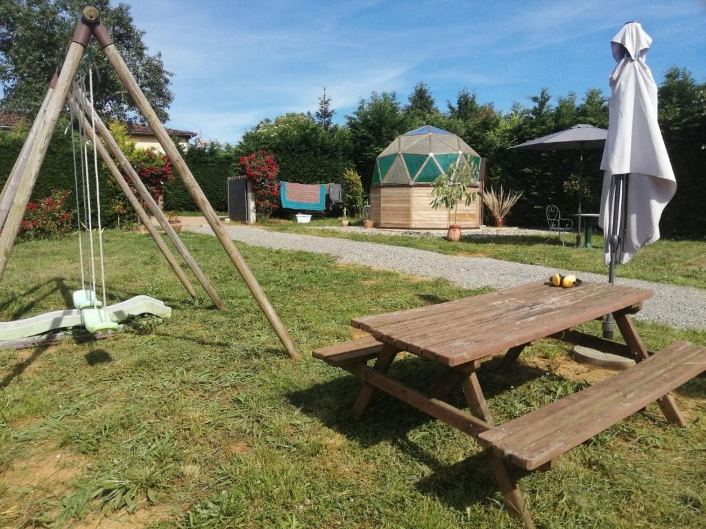 - une table de pique-nique avec un parasol et une balançoire dans l'établissement La Tente Tipi au Ranch du Bonheur, à Tourtouse