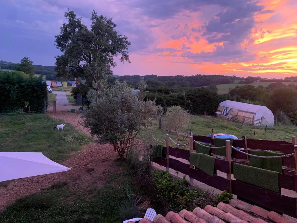 un coucher de soleil sur un champ avec une clôture et des tentes dans l'établissement La Tente Tipi au Ranch du Bonheur, à Tourtouse 4 autres photos