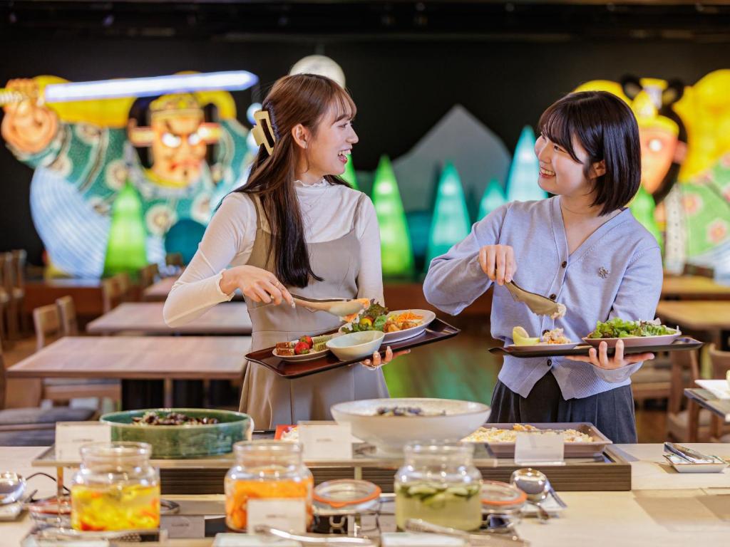 deux femmes qui détiennent des assiettes de nourriture dans un restaurant dans l'établissement Kamenoi Hotel Tsukubasan, à Tsukuba