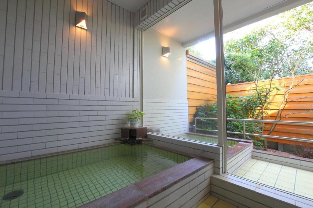 une piscine dans une maison avec une fenêtre dans l'établissement 和みの宿 弓ヶ浜いち番館, à Minamiizu