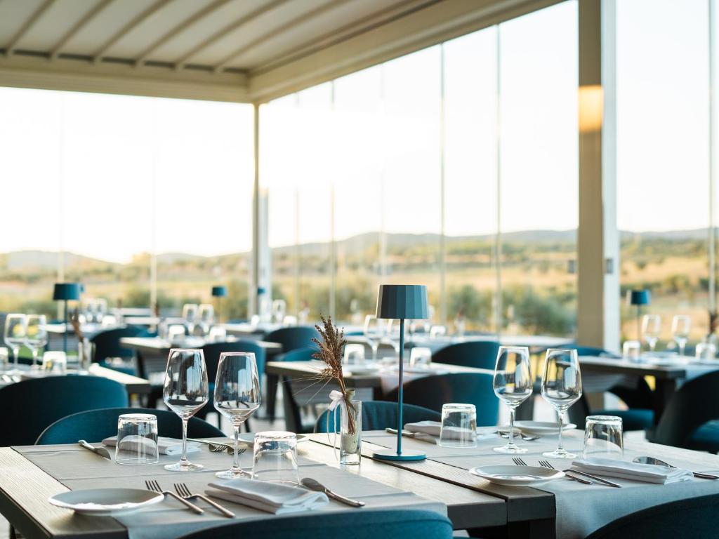 une salle à manger avec des tables, des chaises et des verres à vin dans l'établissement Riva Toscana Golf Resort & SPA, à Follonica
