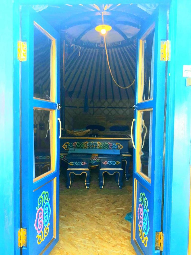 une pièce bleue avec deux chaises et un banc à travers des portes dans l'établissement Yourte du pied de loup, à Saint-Thibault