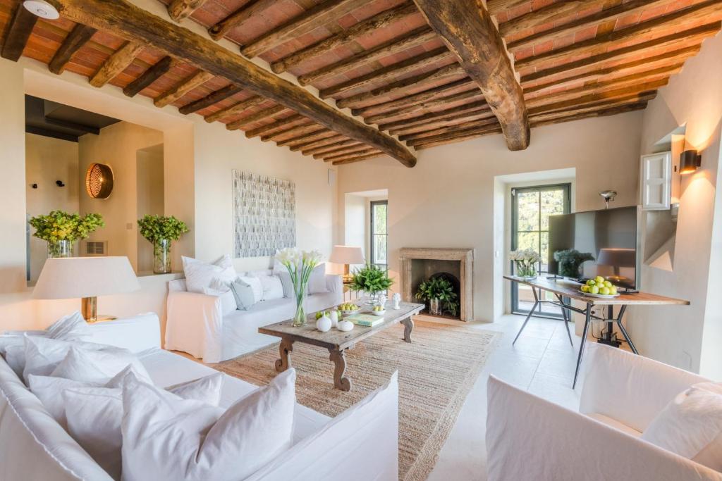 Elle comprend un salon doté d'un mobilier blanc et d'un plafond en bois. dans l'établissement Villa Sunset, Luxury Farmhouse with Infinity Pool, à Lucques