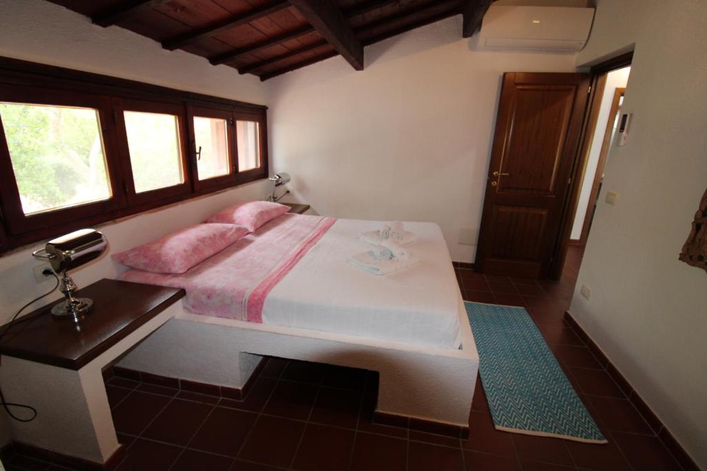 une chambre avec un lit avec des oreillers roses dessus dans l'établissement Domus Cristianae Villa Exclusive Pool Sea View, à Nuragheddu 69 autres photos