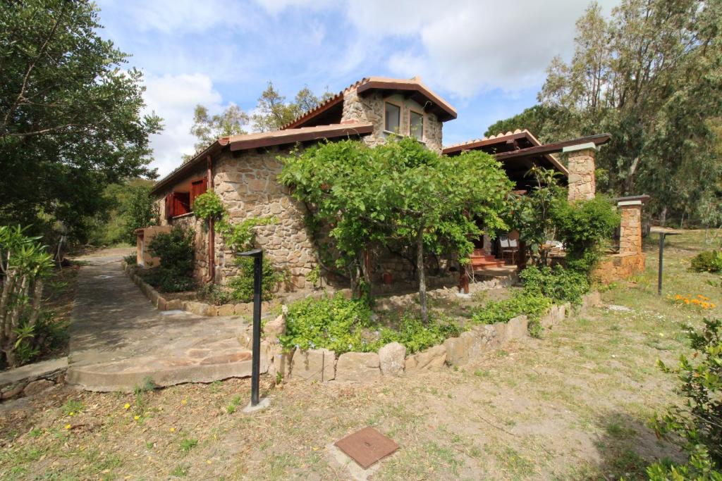 une maison en pierre avec un jardin en face dans l'établissement Domus Cristianae Villa Exclusive Pool Sea View, à Nuragheddu