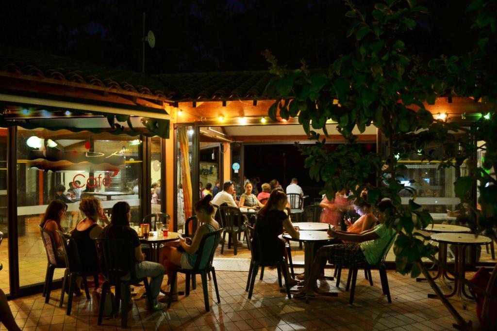 des gens assis à des tables dans un restaurant le soir dans l'établissement Camping la Sousta****, à Remoulins