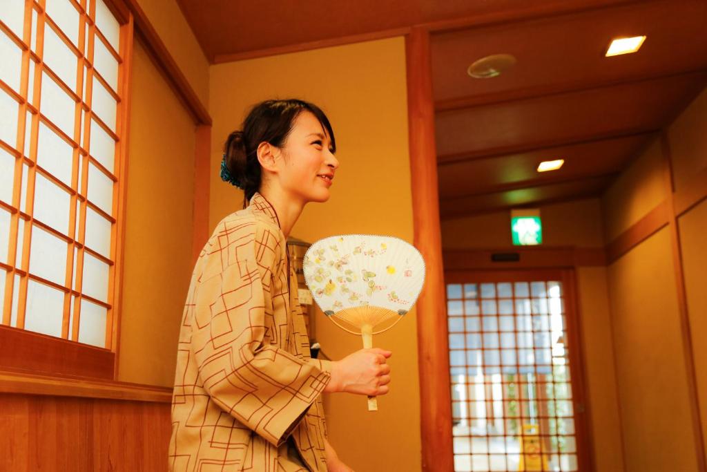 une femme debout dans une pièce tenant un ventilateur dans l'établissement Ako Onsen Shokichi, à Ako 125 autres photos