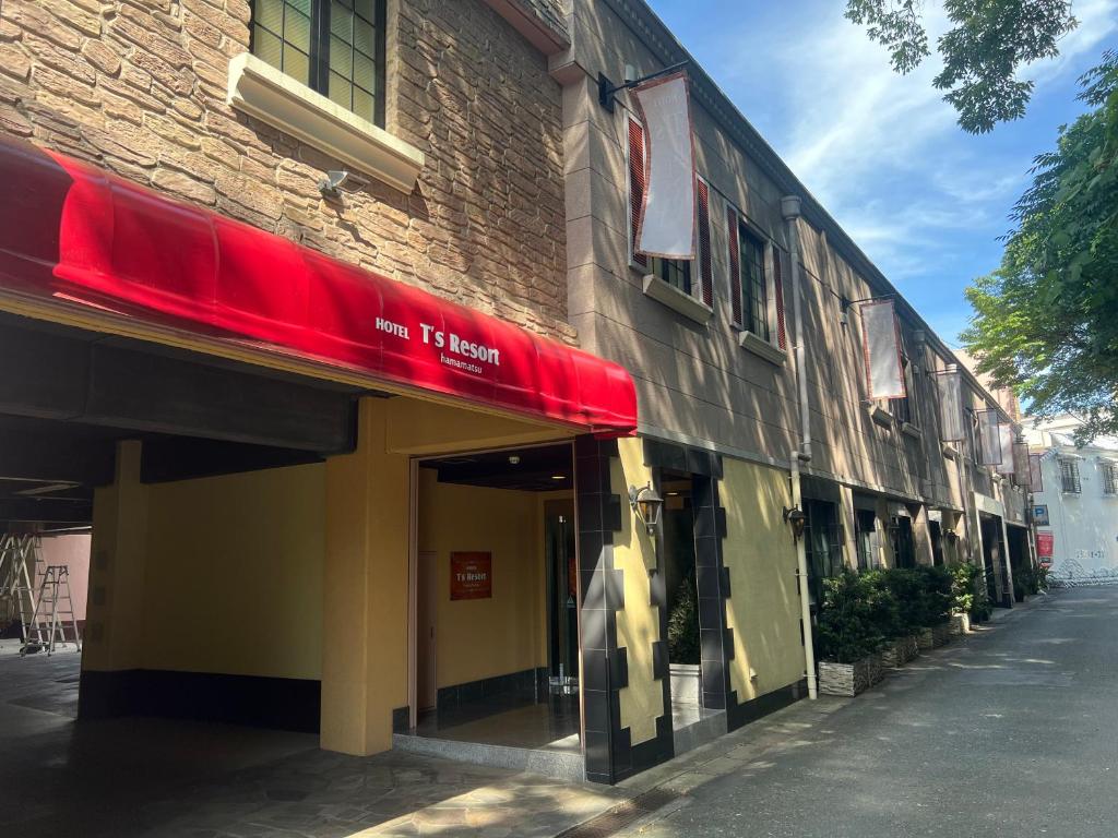 un bâtiment avec un auvent rouge dans une rue dans l'établissement T's Resort HAMAMATSU, à Hamamatsu