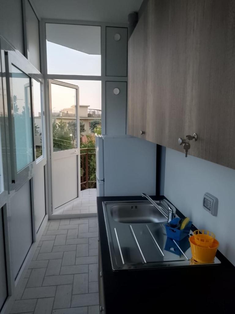 une cuisine avec un évier et une porte ouverte dans l'établissement Gianola Residence Monolocali Formia, à Formia
