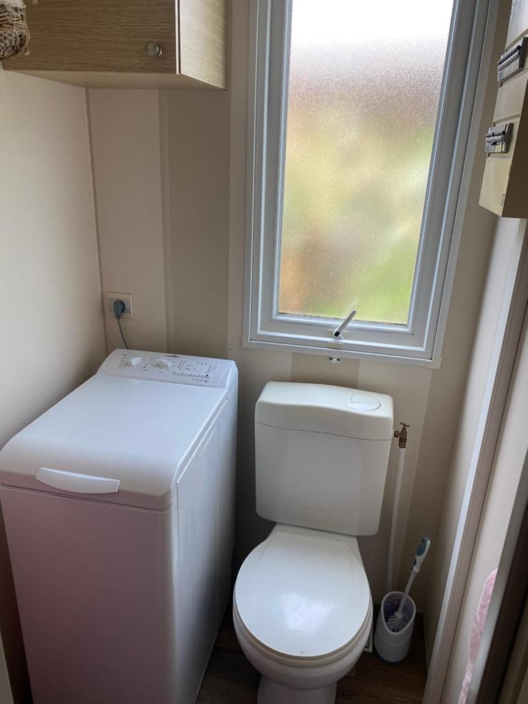 Elle comprend une petite salle de bains pourvue de toilettes et d'une fenêtre. dans l'établissement Mobil Home dans le camping 4 étoiles le Montourey, à Fréjus
