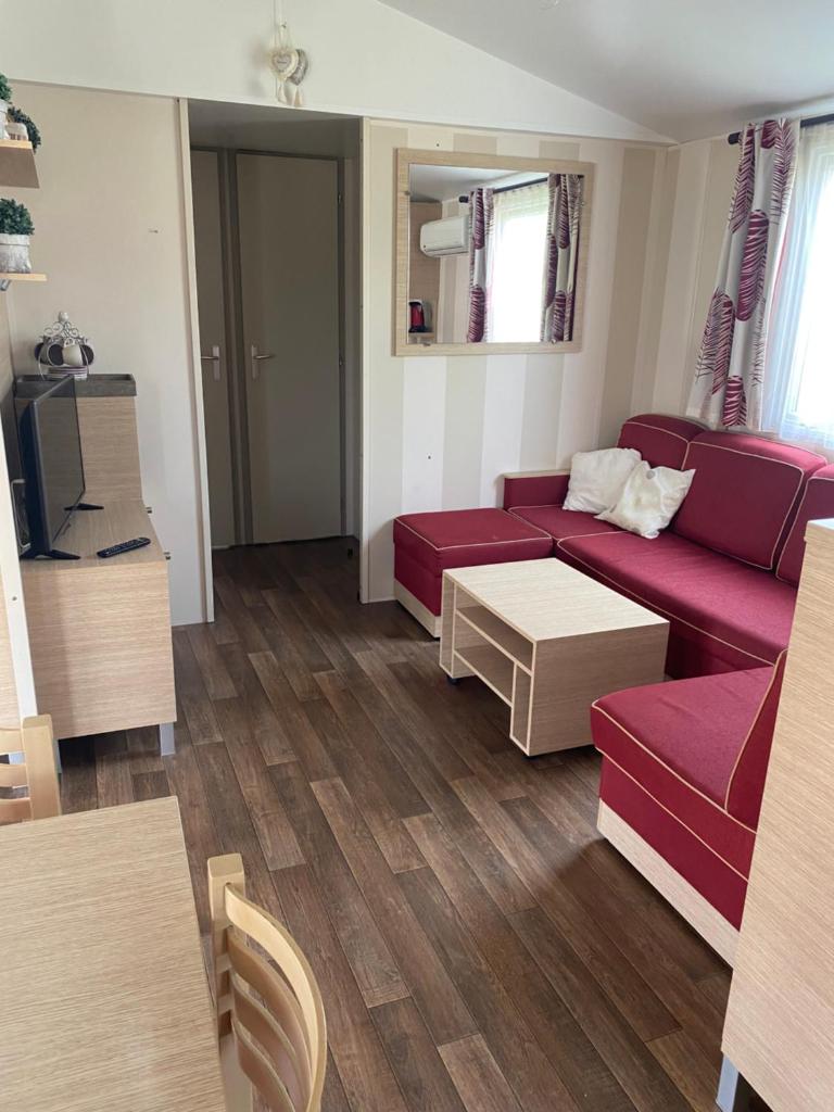 un salon avec un canapé rouge et une table dans l'établissement Mobil Home dans le camping 4 étoiles le Montourey, à Fréjus