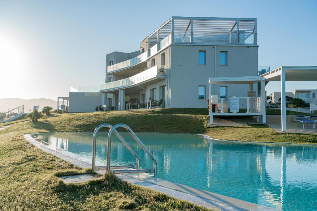 une maison avec une piscine à côté d'un bâtiment dans l'établissement Bellevue Sardinia Resort Affiliated by Meliá, à Valledoria