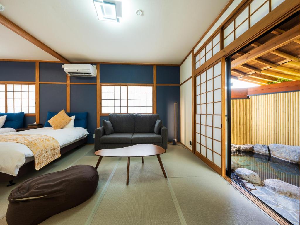 une chambre avec un lit, un canapé et une chaise dans l'établissement Yufuin Hanarenoyado Yukagetsu, à Yufu