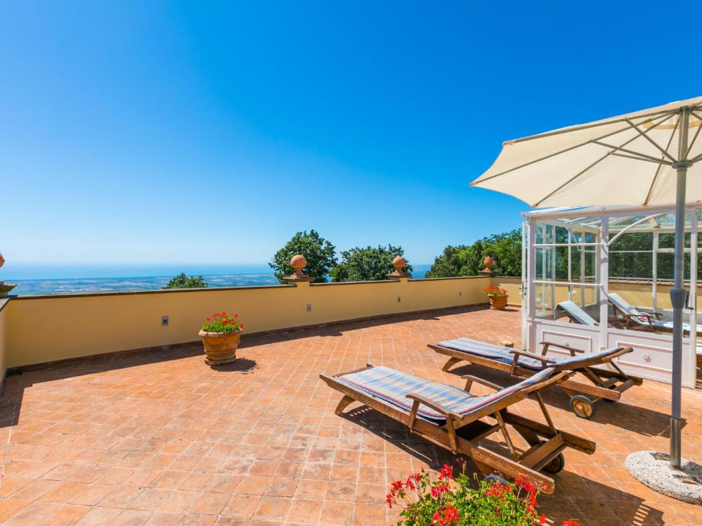 - une terrasse avec 2 tables de pique-nique et un parasol dans l'établissement Villa Poggio al Pruno by Interhome, à Sassa