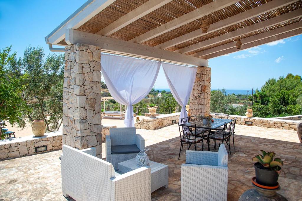 un patio extérieur avec une table, des chaises et un toit dans l'établissement Villa Luce, à Leuca