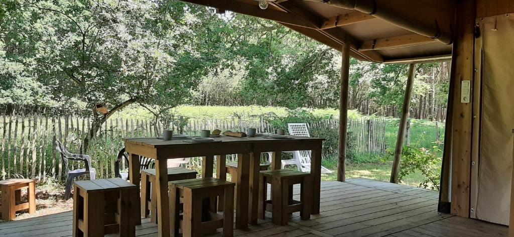une table et des chaises en bois sur une terrasse en bois dans l'établissement eco lodge 4 etoiles cotton prenium, à Vendays-Montalivet