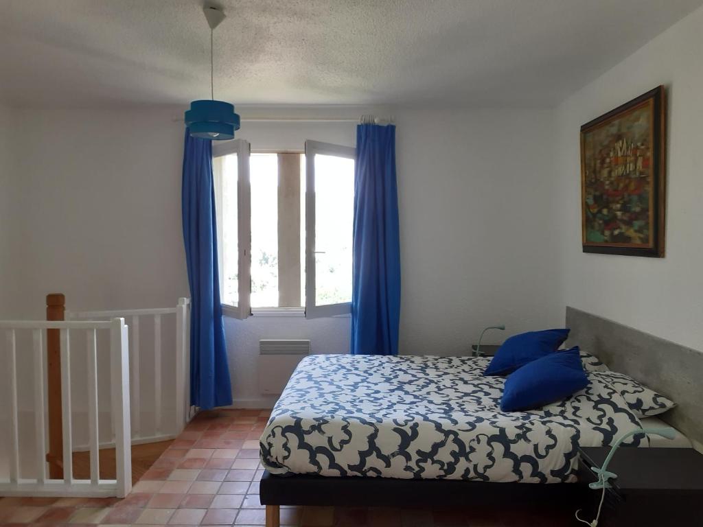 une chambre avec un lit et une fenêtre avec des rideaux bleus dans l'établissement Gîte du vigneron à La Terrasse piscine local vélos, à Tournon-sur-Rhône