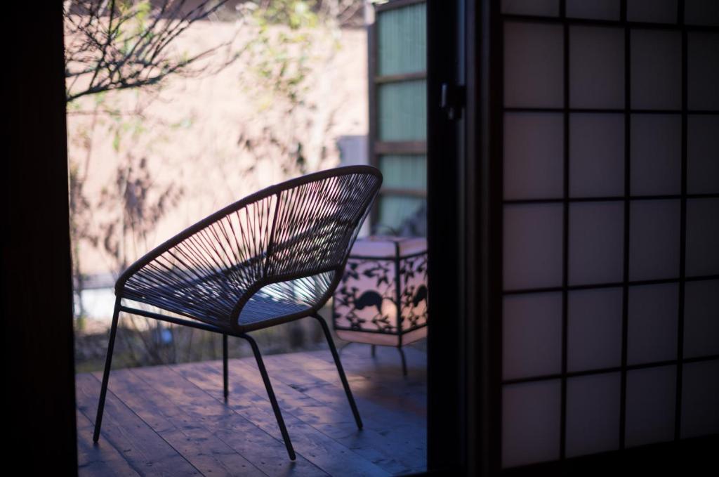 une chaise assise sur une terrasse à l'extérieur d'une porte dans l'établissement Yufuin Kaze no Mori, à Yufu