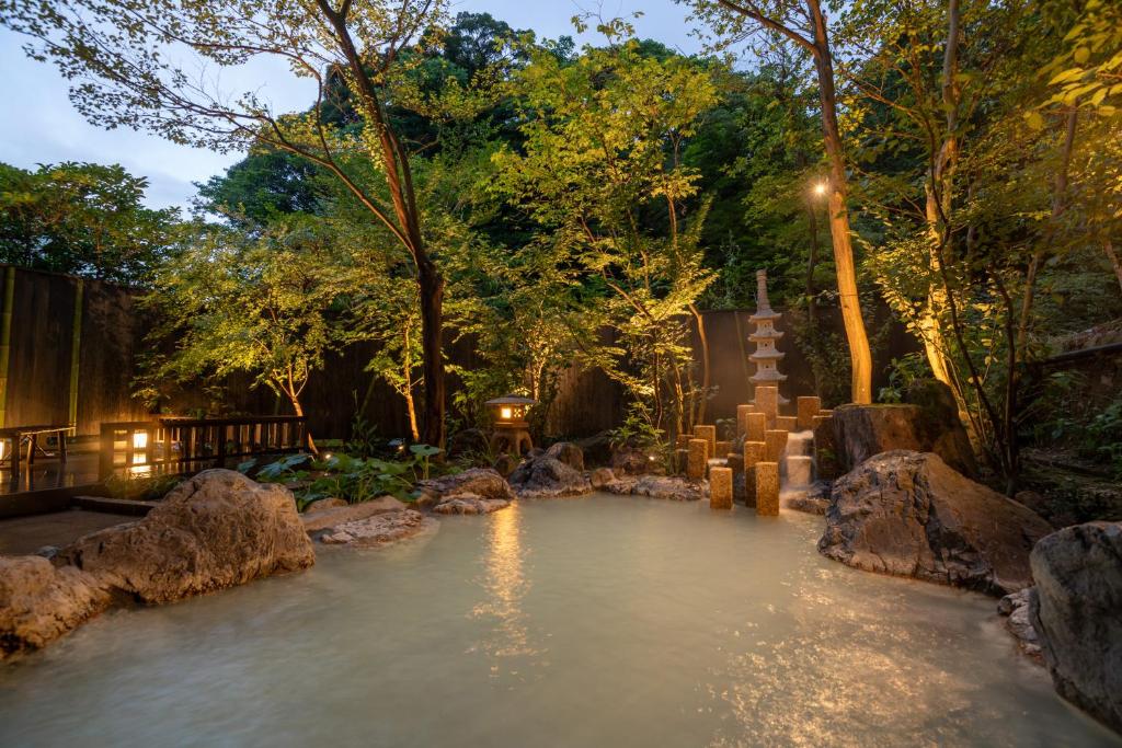 un étang dans un jardin avec des rochers et des arbres dans l'établissement Kirishima Kokusai Hotel, à Kirishima