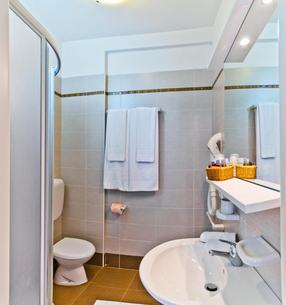 une salle de bain avec un lavabo et des toilettes dans l'établissement Hotel Victoria, à Bibione