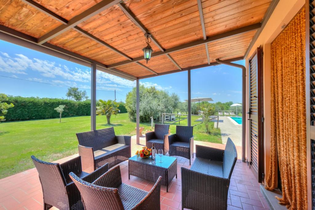 un patio extérieur avec des chaises, des tables et un auvent dans l'établissement Villa San Lorenzo - Happy Rentals, à Cortone