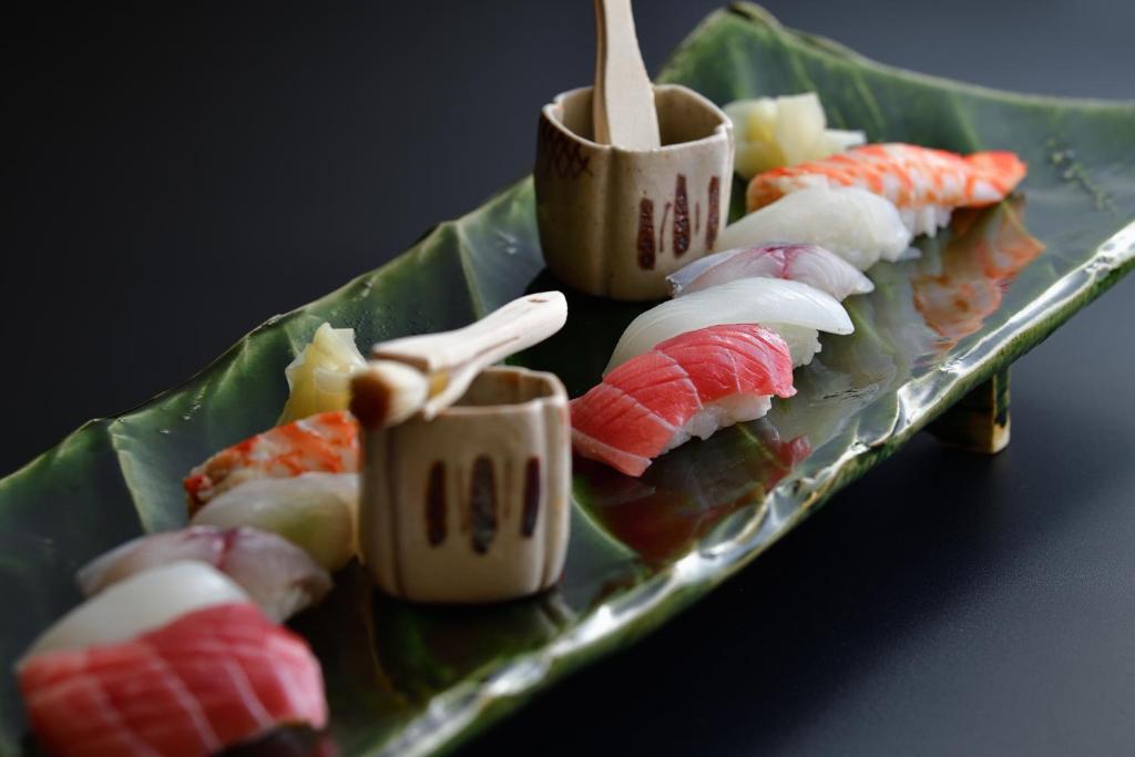 une assiette de sushi avec des baguettes dessus dans l'établissement Shima Onsen Yoshimoto, à Nakanojo