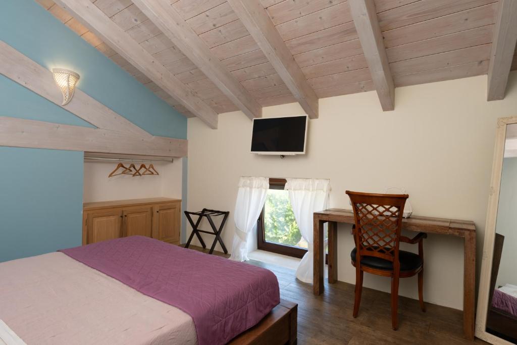 une chambre avec un lit, un bureau et une télévision dans l'établissement Palascìa Wellness Relais, à Otrante