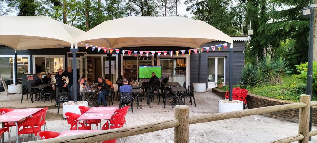 un restaurant avec des chaises rouges, des tables et des parasols dans l'établissement Magnifique mobil-home ensoleillé 6 couchages à une heure de Paris, à Saint-Chéron