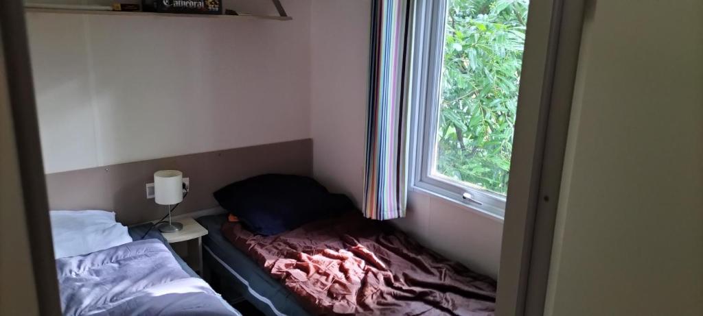 une petite pièce avec un lit et une fenêtre dans l'établissement Magnifique mobil-home ensoleillé 6 couchages à une heure de Paris, à Saint-Chéron