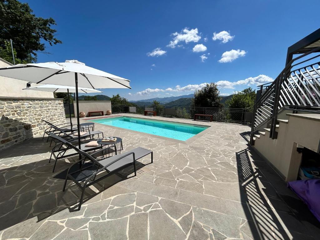 une piscine avec deux chaises et un parasol dans l'établissement Poggio Ancisa Relais, à Casteldelci