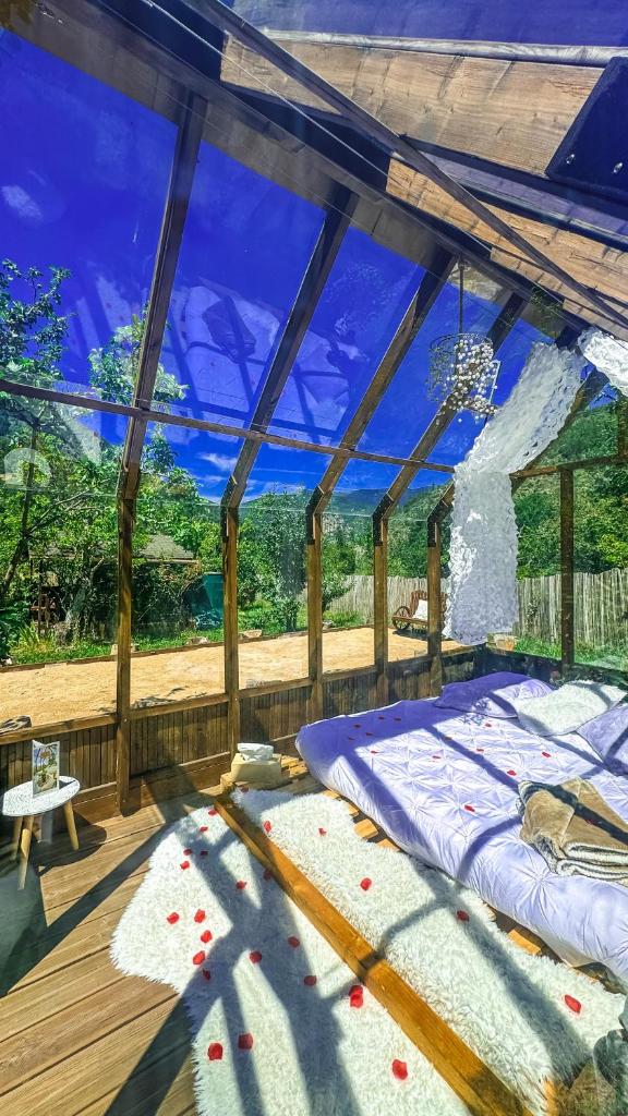 un lit dans une chambre avec une grande fenêtre dans l'établissement Chalet en verre sous une pluie étoilée, à Lantosque