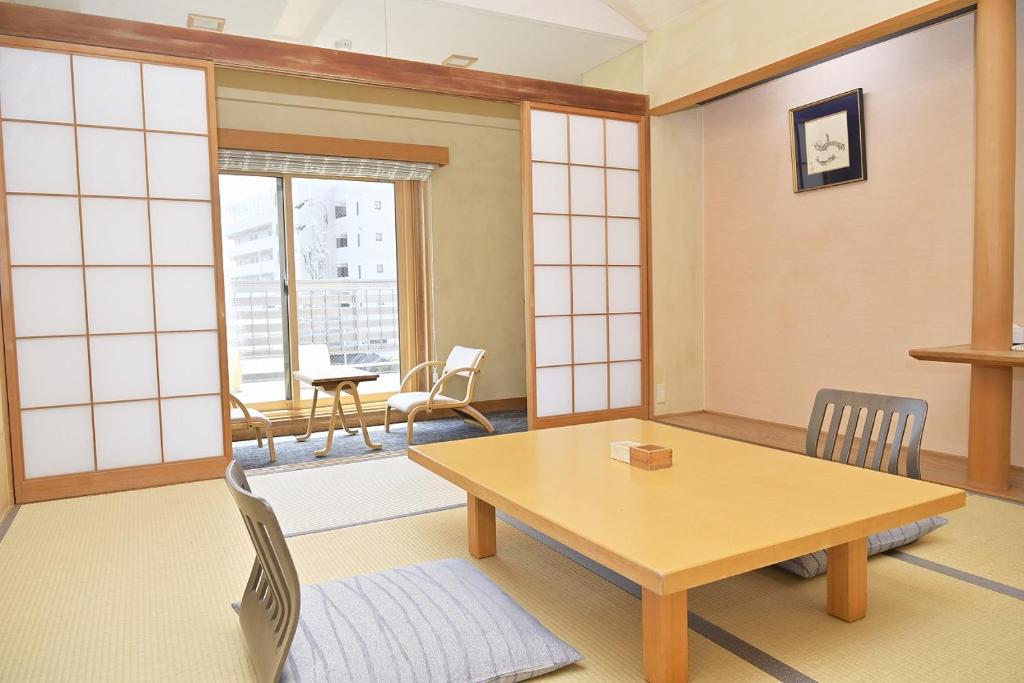 une salle à manger avec une table, des chaises et des fenêtres dans l'établissement Kansuitei Kozeniya, à Tottori