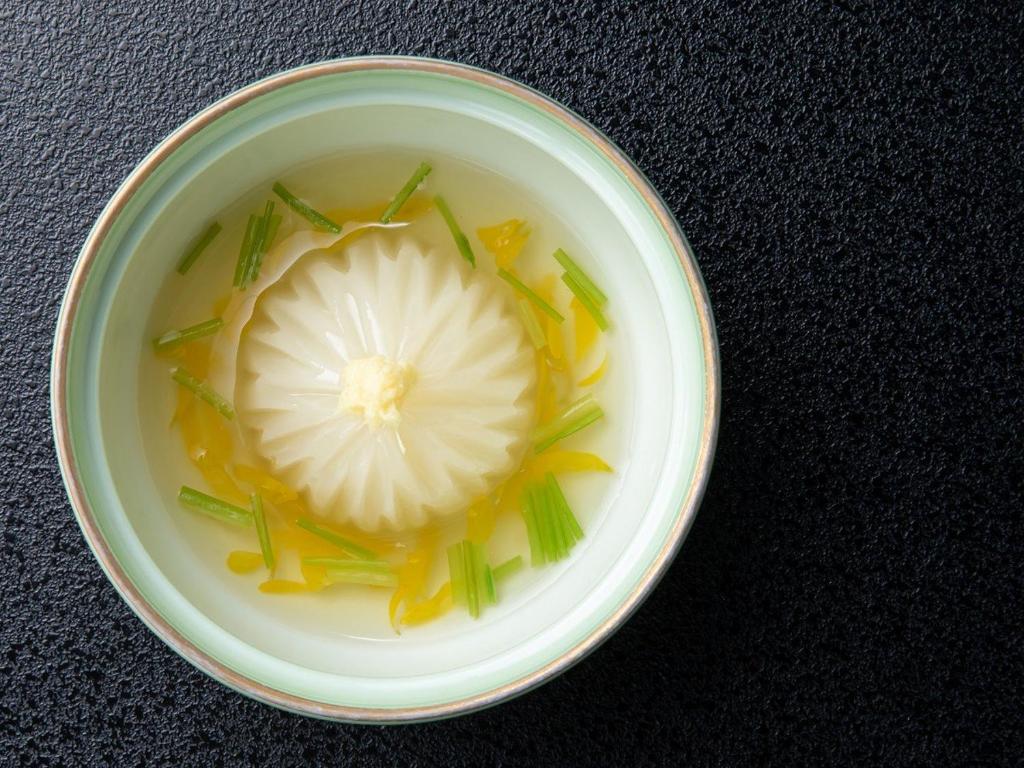 un bol de soupe avec un oignon et des oignons verts dans l'établissement Chousenkaku Kameya, à Shimo-suwa