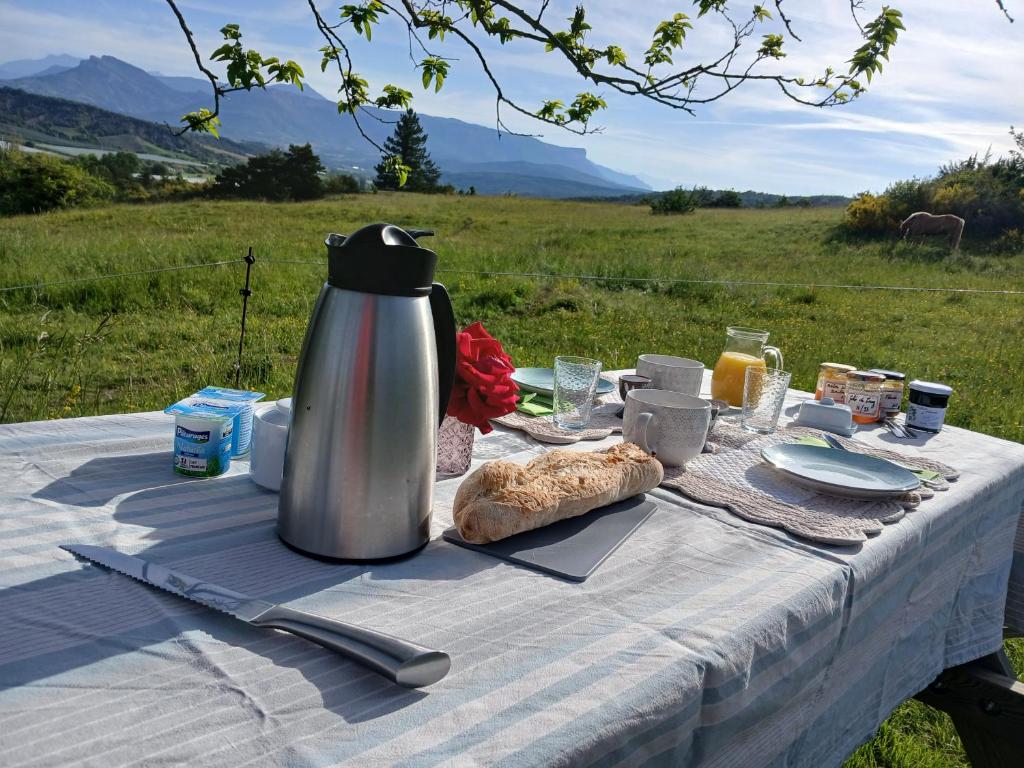 une table de pique-nique avec un thermos et du pain dessus dans l'établissement Camping insolite pleine nature, à Orpierre