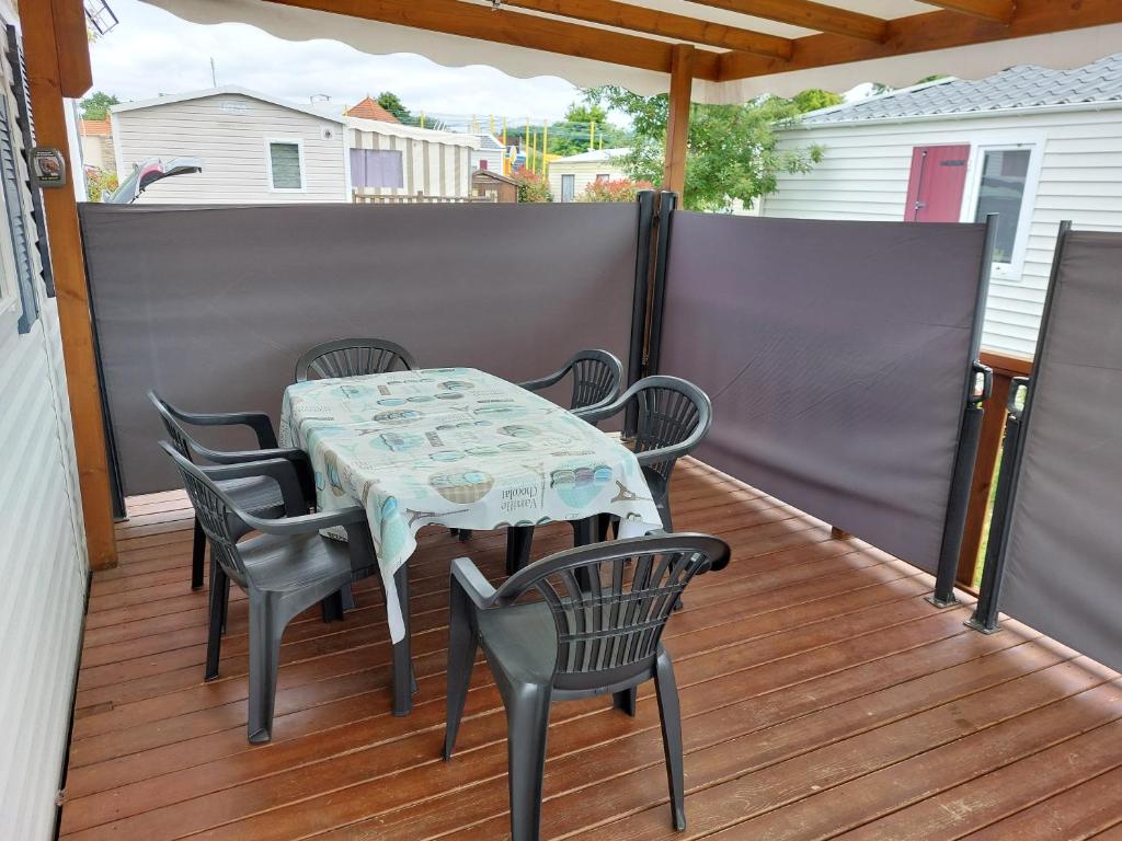 une table et des chaises assises sur une terrasse avec une table et des chaises dans l'établissement mobil home camping 3 etoiles les ollivaud, à La Baule