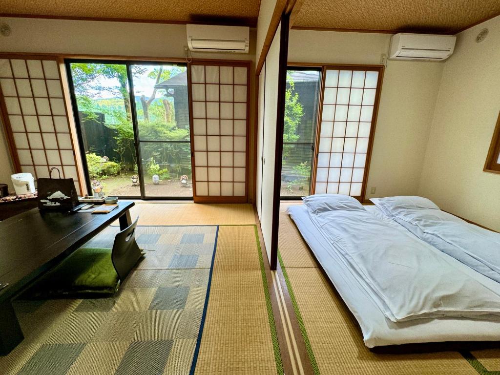 une chambre avec un lit, un bureau et des fenêtres dans l'établissement Oyado Tamayura 18 years or older, à Yufu