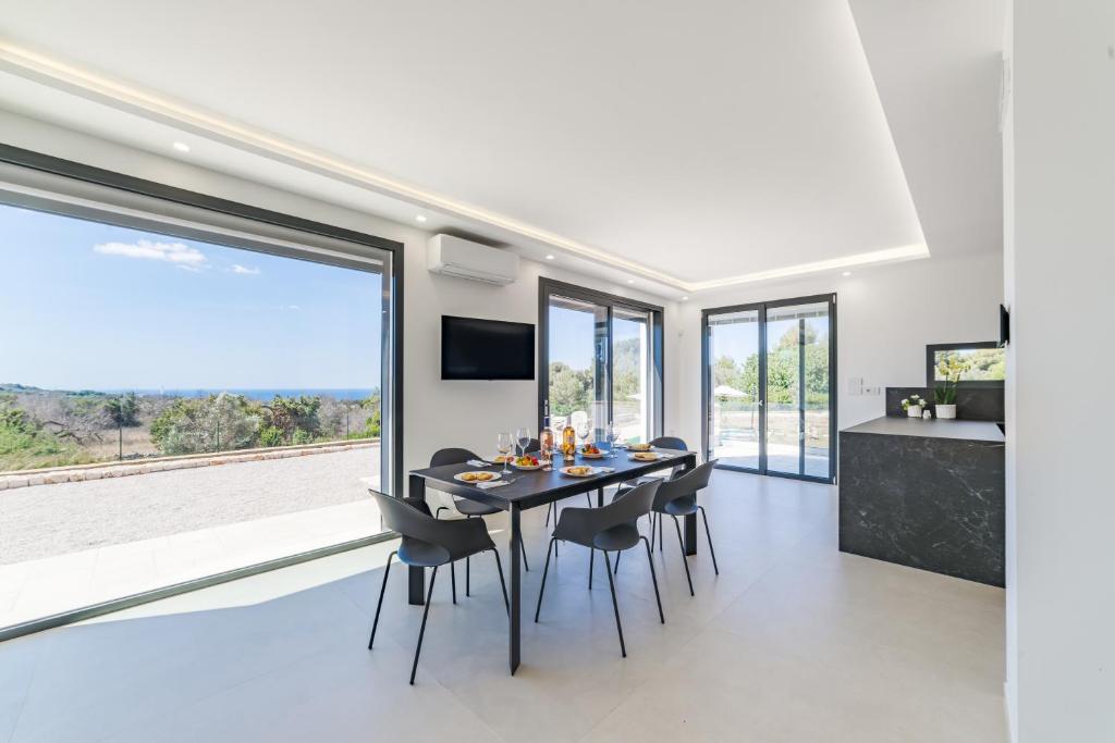 une salle à manger avec une table et des chaises et une grande fenêtre dans l'établissement Villa Lorenbea by salentoltremare, à Castrignano del Capo