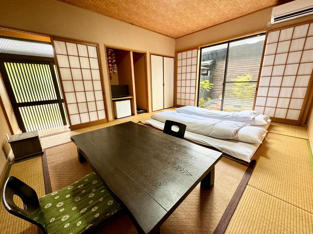 une pièce avec une table, un lit et des fenêtres dans l'établissement Oyado Tamayura 18 years or older, à Yufu 40 autres photos