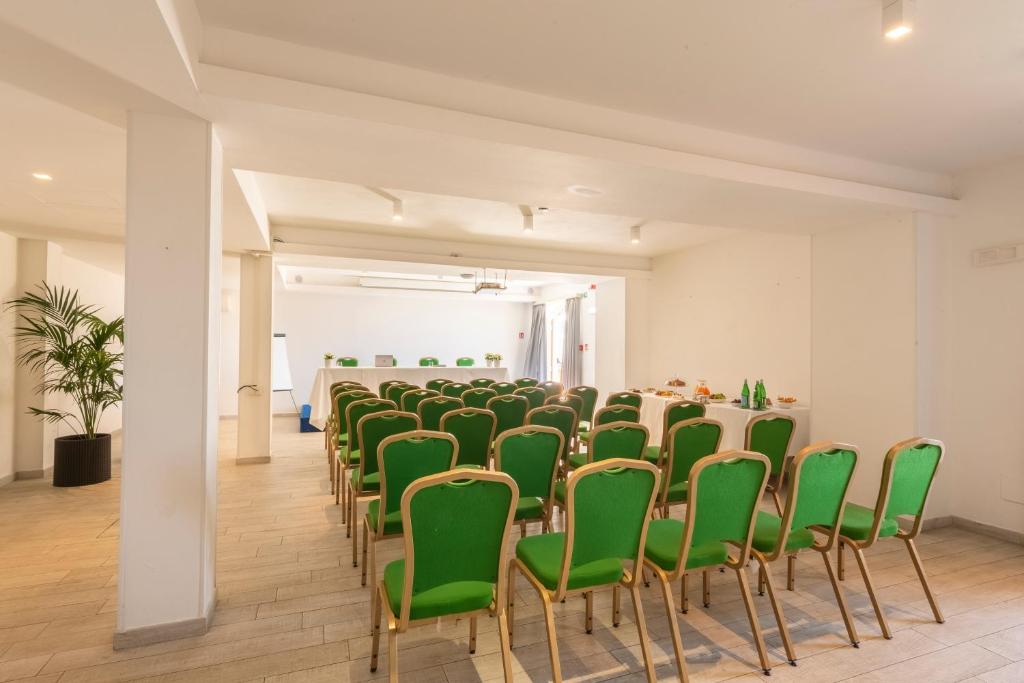 une pièce avec une rangée de chaises et de tables vertes dans l'établissement Boutique Hotel Torre Di Cala Piccola, à Porto Santo Stefano