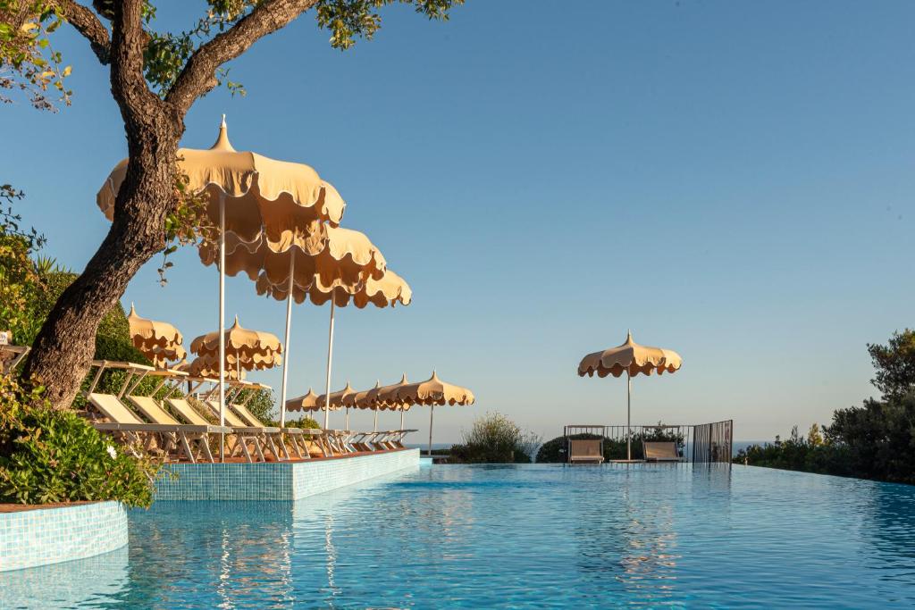 - une piscine avec parasols et chaises dans l'établissement Boutique Hotel Torre Di Cala Piccola, à Porto Santo Stefano