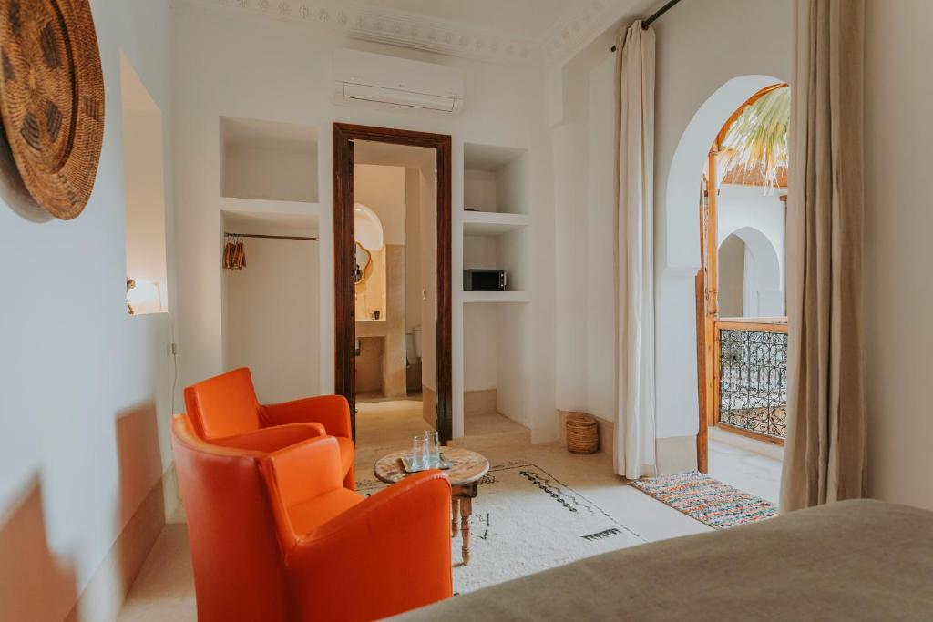 un salon avec des chaises orange et une table dans l'établissement Riad Djebel, à Marrakech