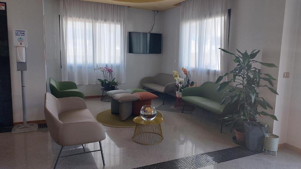 - un salon avec des canapés, des chaises et une télévision dans l'établissement Albergo Ridente, à Lido di Jesolo