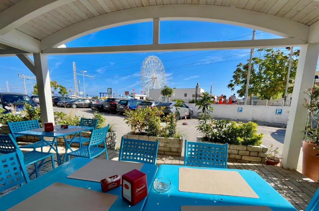 un patio avec des tables et des chaises bleues et une grande roue dans l'établissement B&B Marina Sleep And Ship, à Rodi Garganico 42 autres photos