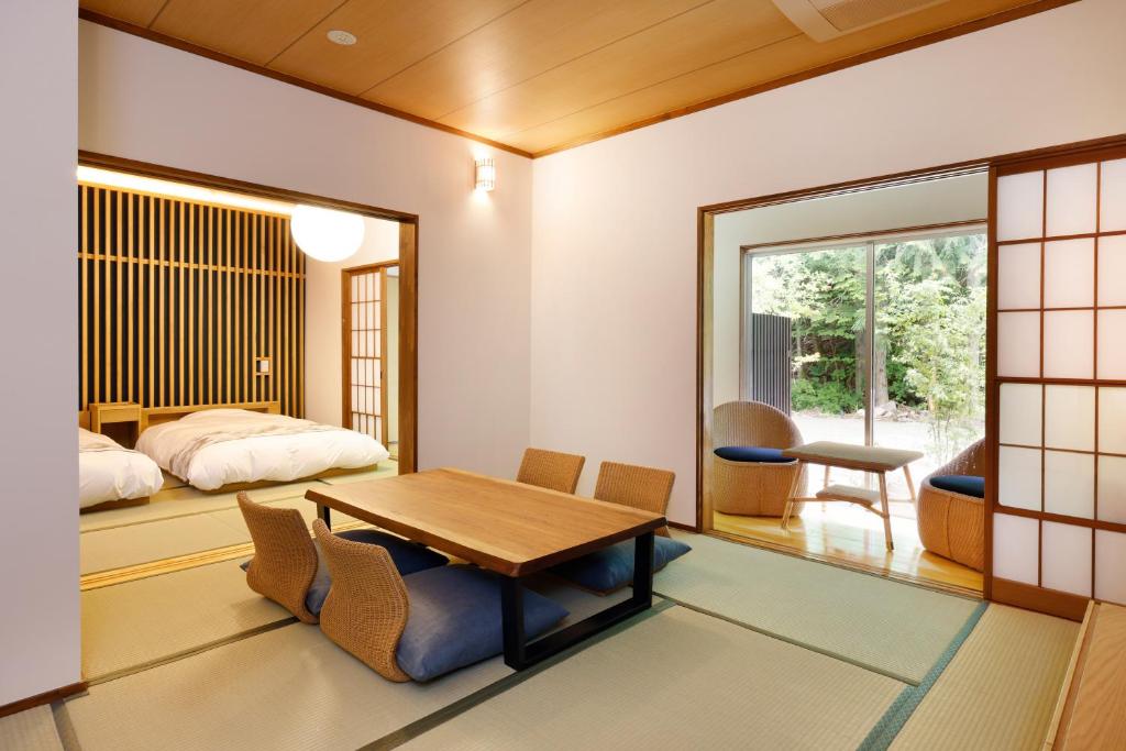une pièce avec une table, des chaises et un lit dans l'établissement 阿智星降りの宿やま星 Hotel&Glamp YAMABOSHI, à Achi