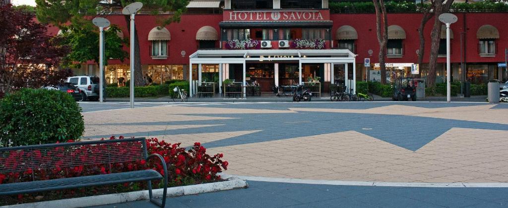 un banc devant un bâtiment avec un magasin dans l'établissement Hotel Savoia, à Lignano Sabbiadoro