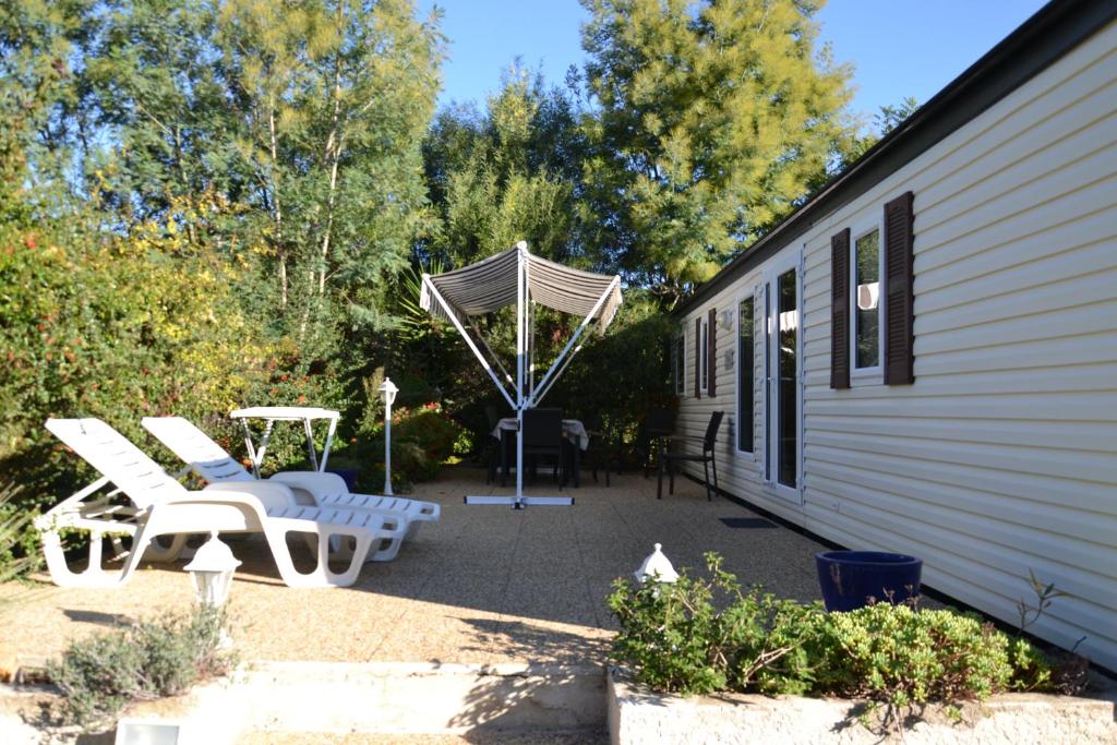 - une terrasse avec 2 chaises blanches et un parasol dans l'établissement Camping Parc Valrose, à La Londe-les-Maures 25 autres photos