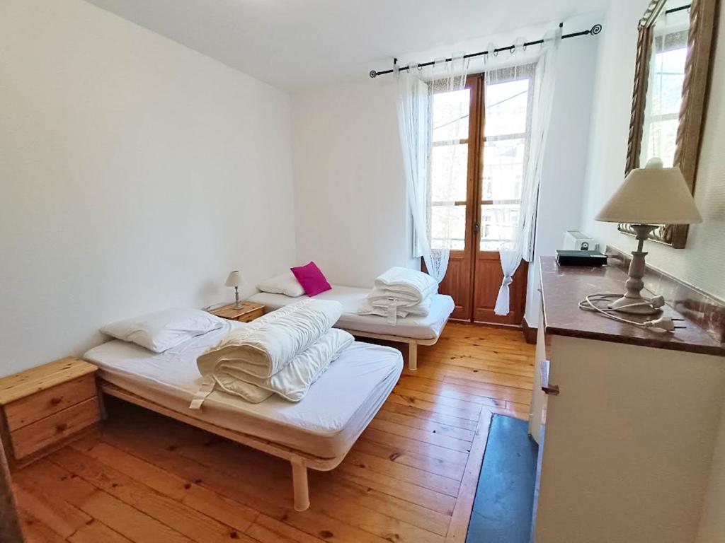 - 2 lits dans une chambre dotée de parquet et de fenêtres dans l'établissement Le petit cerf, T3, wifi, cave, à Luchon