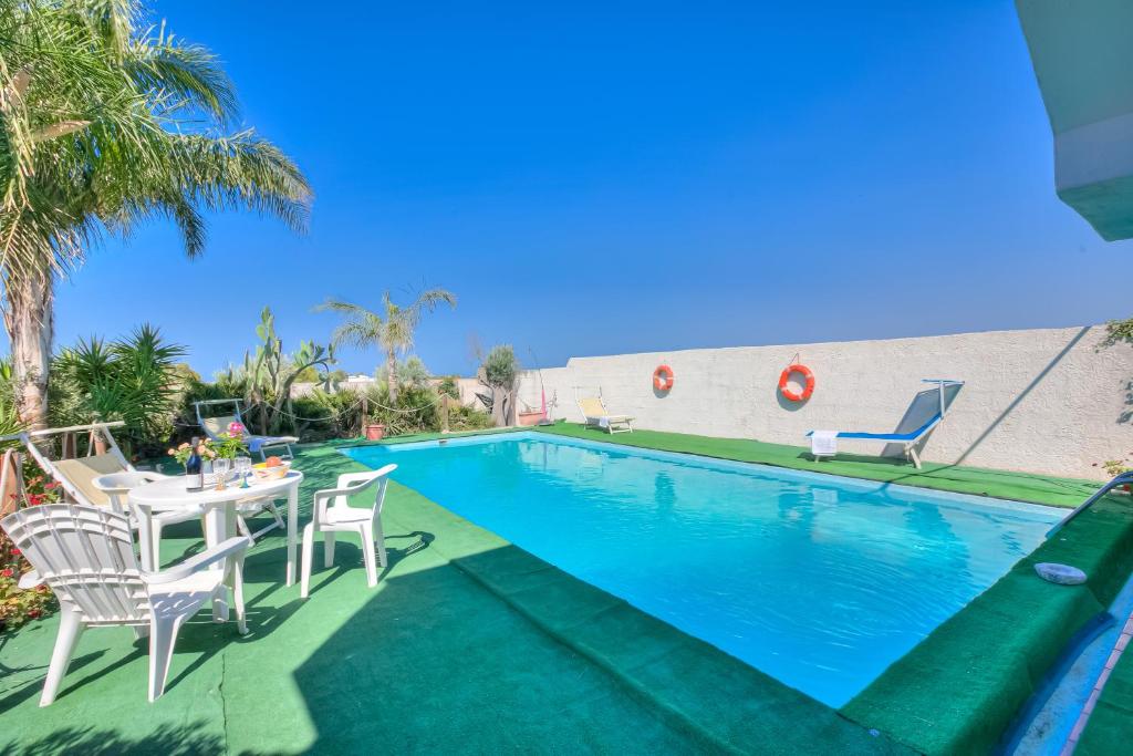 - une piscine avec une table et des chaises à côté dans l'établissement Villa Strea With Pool - Happy Rentals, à Porto Cesareo