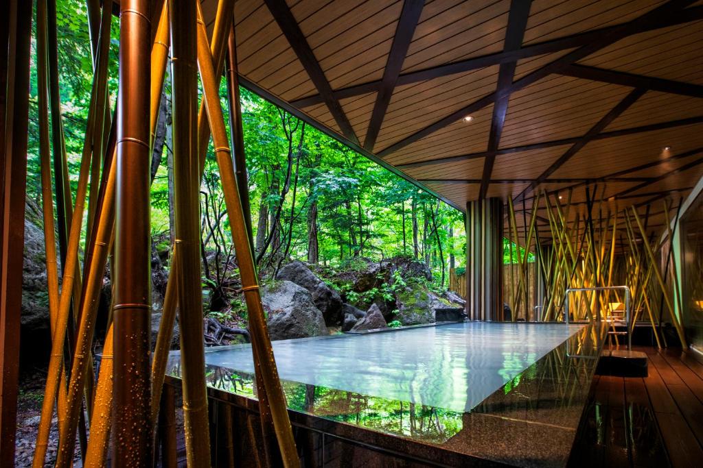 un bâtiment avec une piscine au milieu d'une forêt dans l'établissement Choyo Resort Hotel, à Kamikawa
